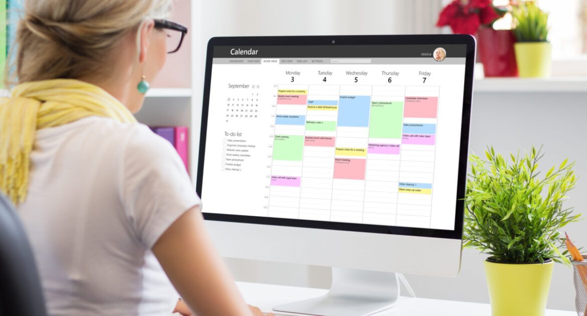Woman using calendar app on computer in office- Time management tools for PhD students