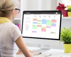Woman using calendar app on computer in office- Time management tools for PhD students