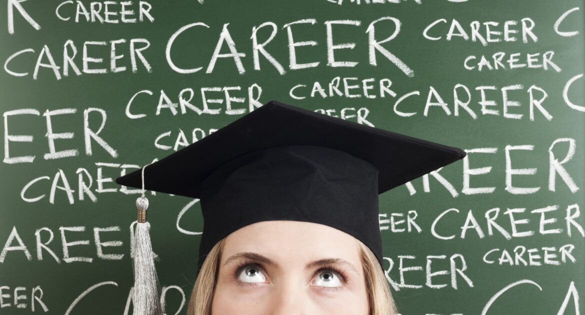 Woman in mortarboard standing in front of chalk words