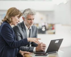 man and woman talking about learning at laptop