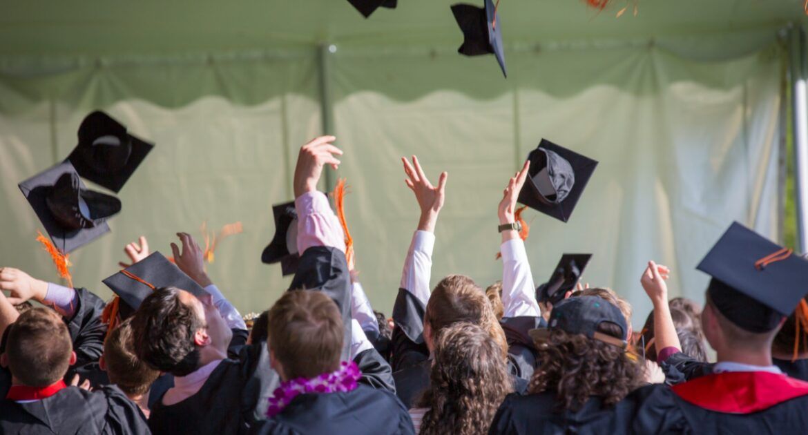 mixed group of graduates throwing mortar boards in air in celebration
